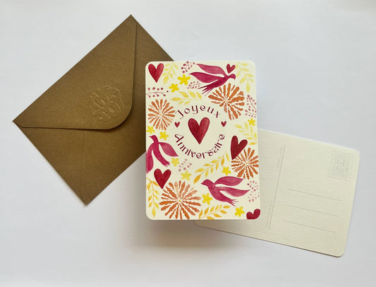 Carte d'anniversaire 'Joyeux Anniversaire' avec coeurs, oiseaux et motifs floraux, accompagnée d'une enveloppe kraft.