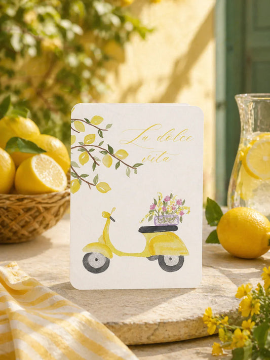Carte 'La dolce vita' avec scooter jaune, citrons et fleurs, ambiance méditerranéenne ensoleillée