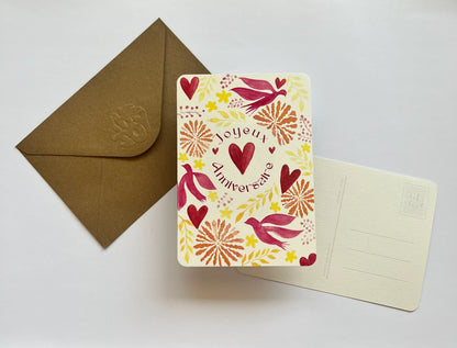 Carte d'anniversaire 'Joyeux Anniversaire' avec coeurs, oiseaux et motifs floraux, accompagnée d'une enveloppe kraft.