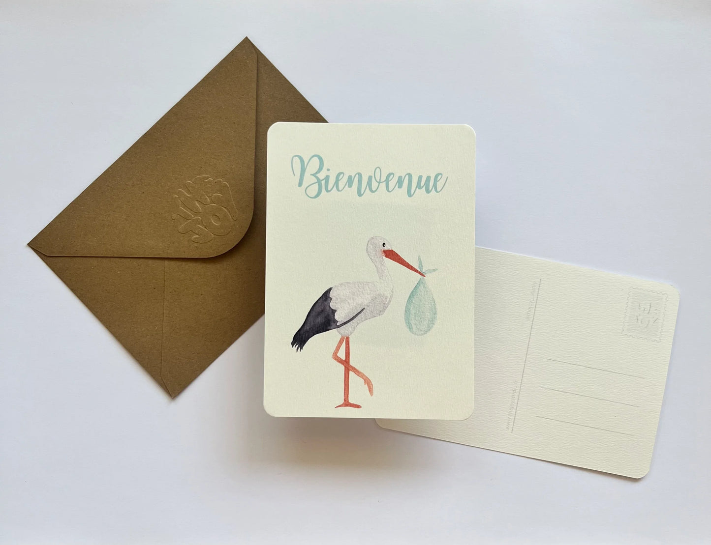 Carte de bienvenue avec cigogne tenant un bébé, enveloppe kraft, design doux et élégant