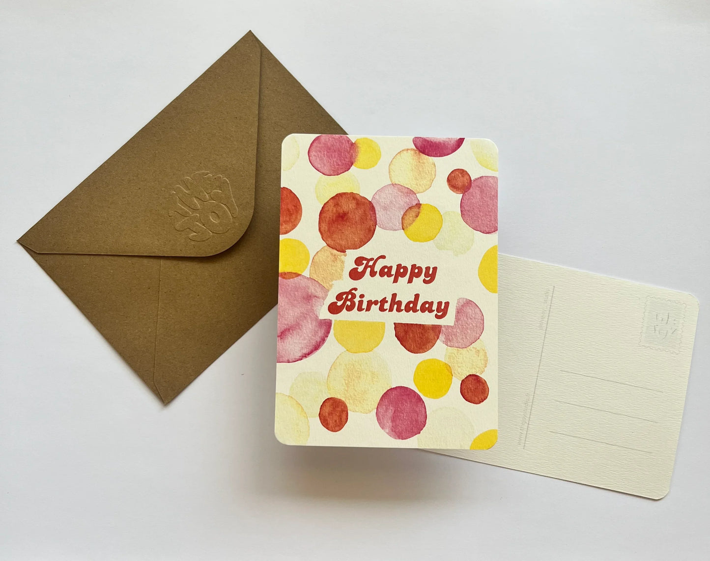 Carte d'anniversaire aquarelle avec motifs colorés et enveloppe kraft, idéale pour un cadeau festif
