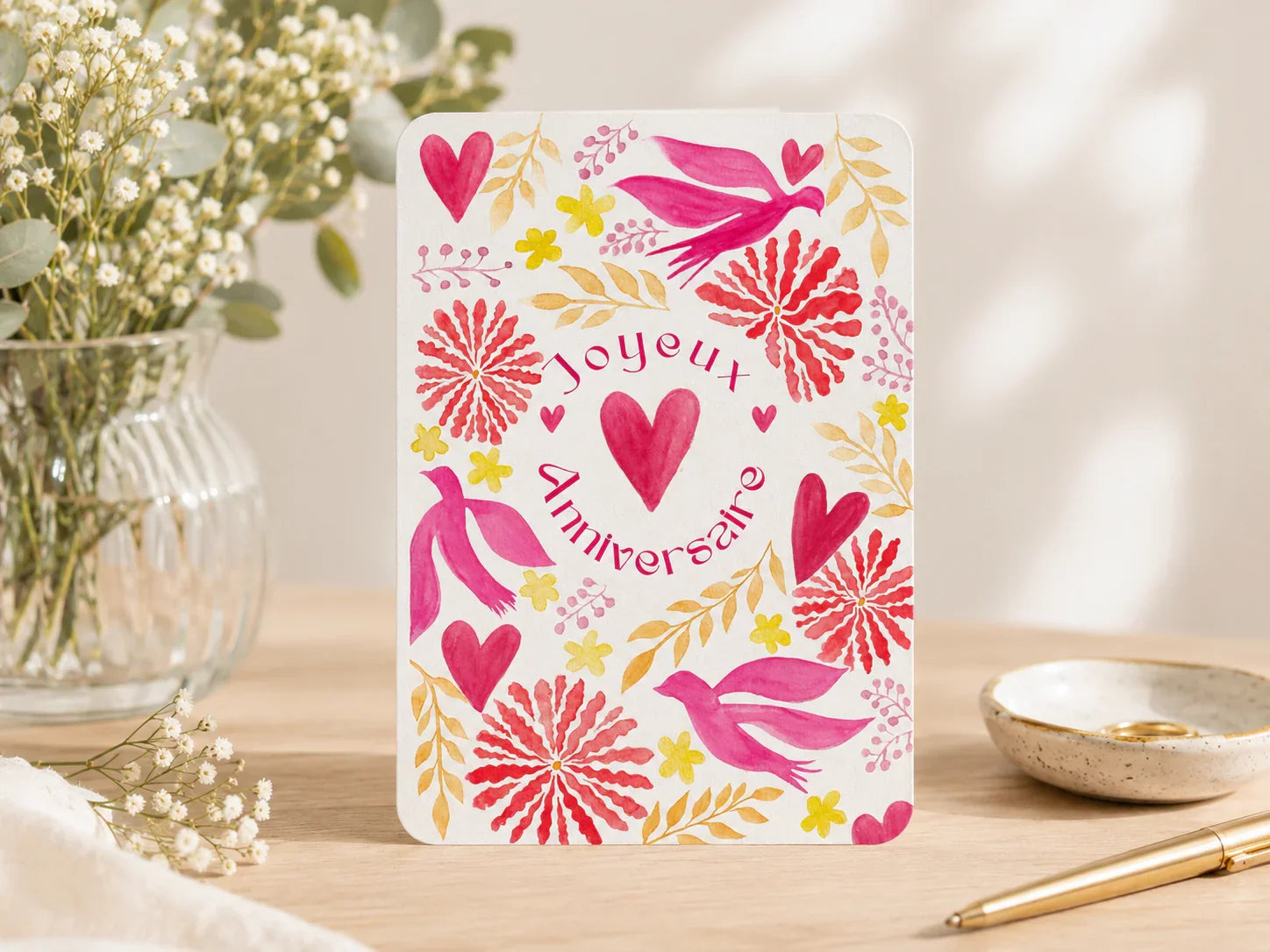 Carte d'anniversaire 'Joyeux Anniversaire' avec coeurs, oiseaux et fleurs roses et jaunes sur fond blanc