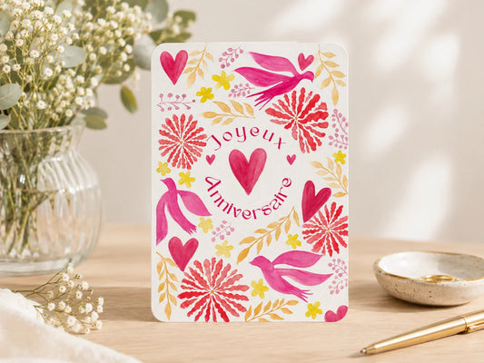 Carte d'anniversaire 'Joyeux Anniversaire' avec coeurs, oiseaux et fleurs roses et jaunes sur fond blanc