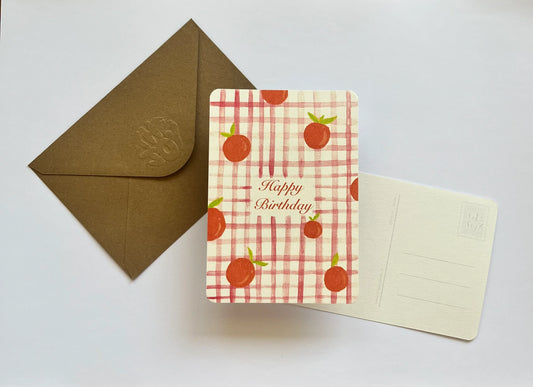 Carte d'anniversaire à motifs fruits sur fond à carreaux, avec enveloppe kraft, design joyeux et coloré.