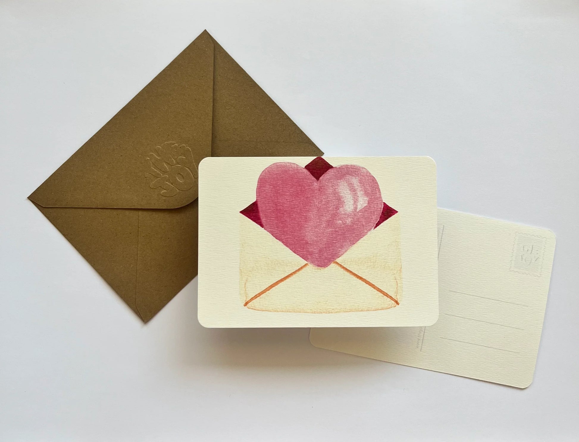Carte postale avec cœur rose et enveloppe kraft, idéale pour message d'amour ou Saint-Valentin
