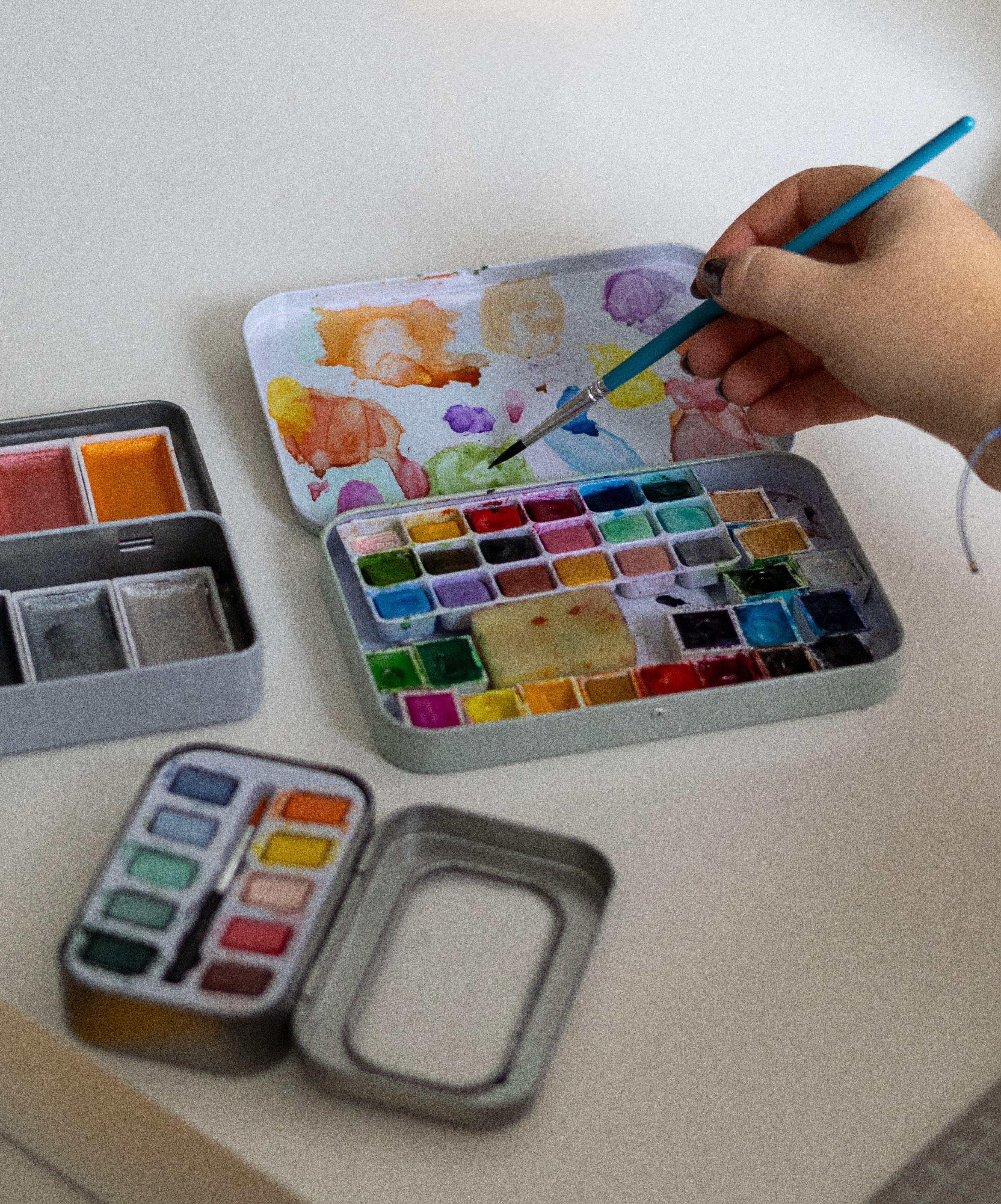 Palette d'aquarelles colorées avec pinceau en action, idéale pour artistes et débutants