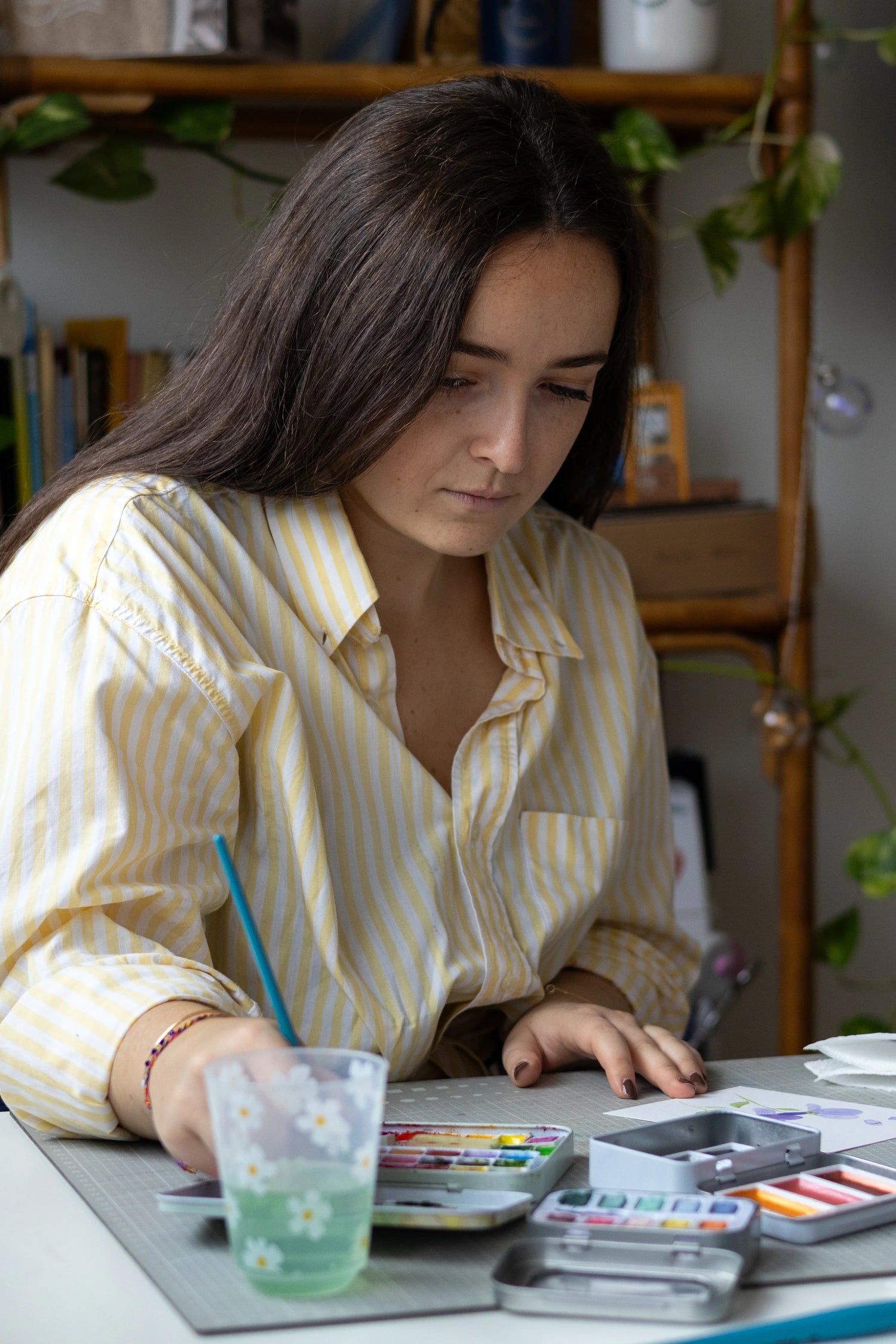 Femme peignant avec des aquarelles dans un atelier lumineux, pinceau et palette de couleurs